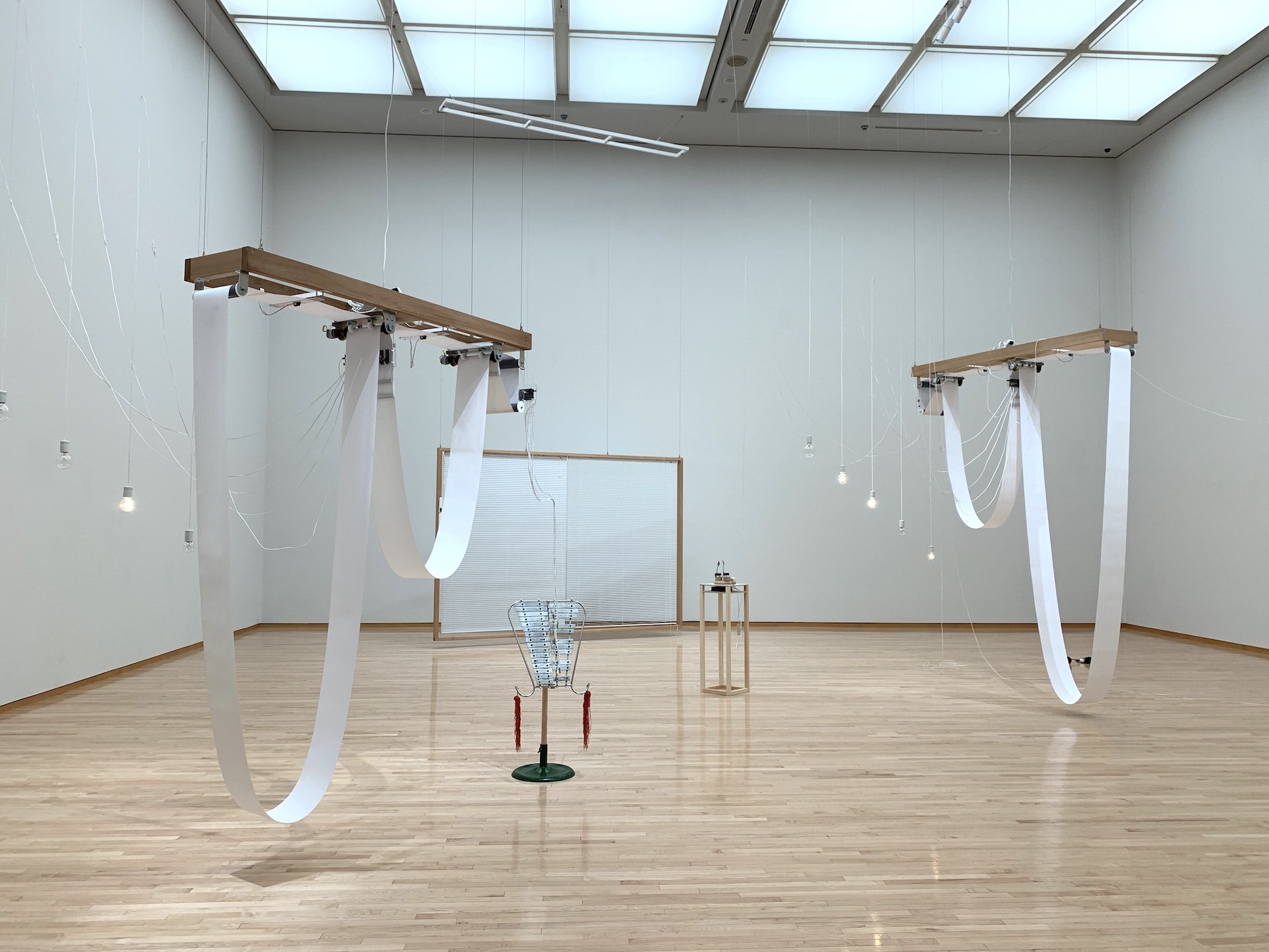 毛利悠子 《I/O I/O》2011〜16年 ロール紙、竹炭、ベルリラ、ハ タキ、ブラインド、電球、ス プーン、モーター、木材など