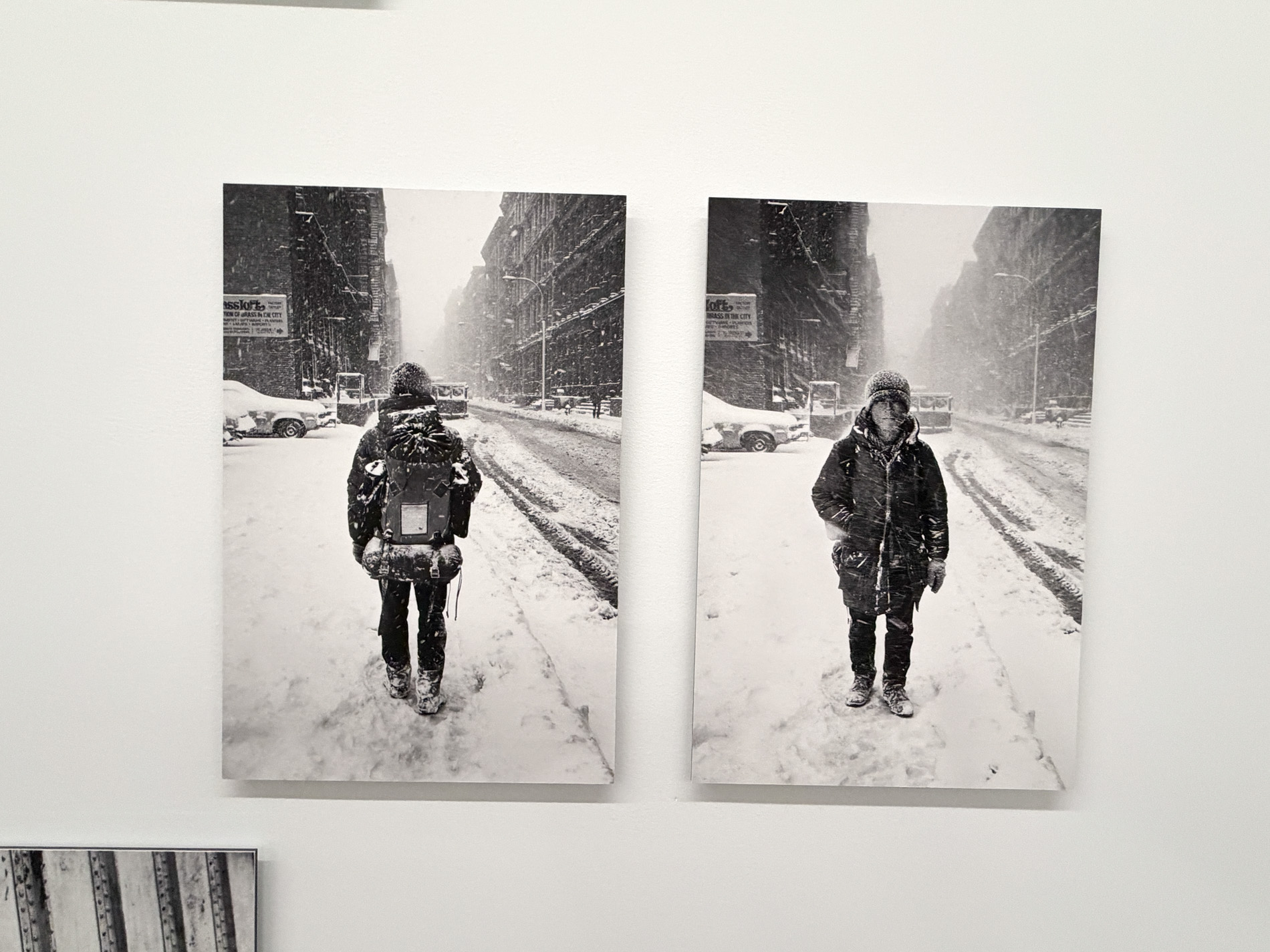 雪の降る通りの真ん中に、荷物を背負った男性が立つ白黒写真が2枚並んでいる