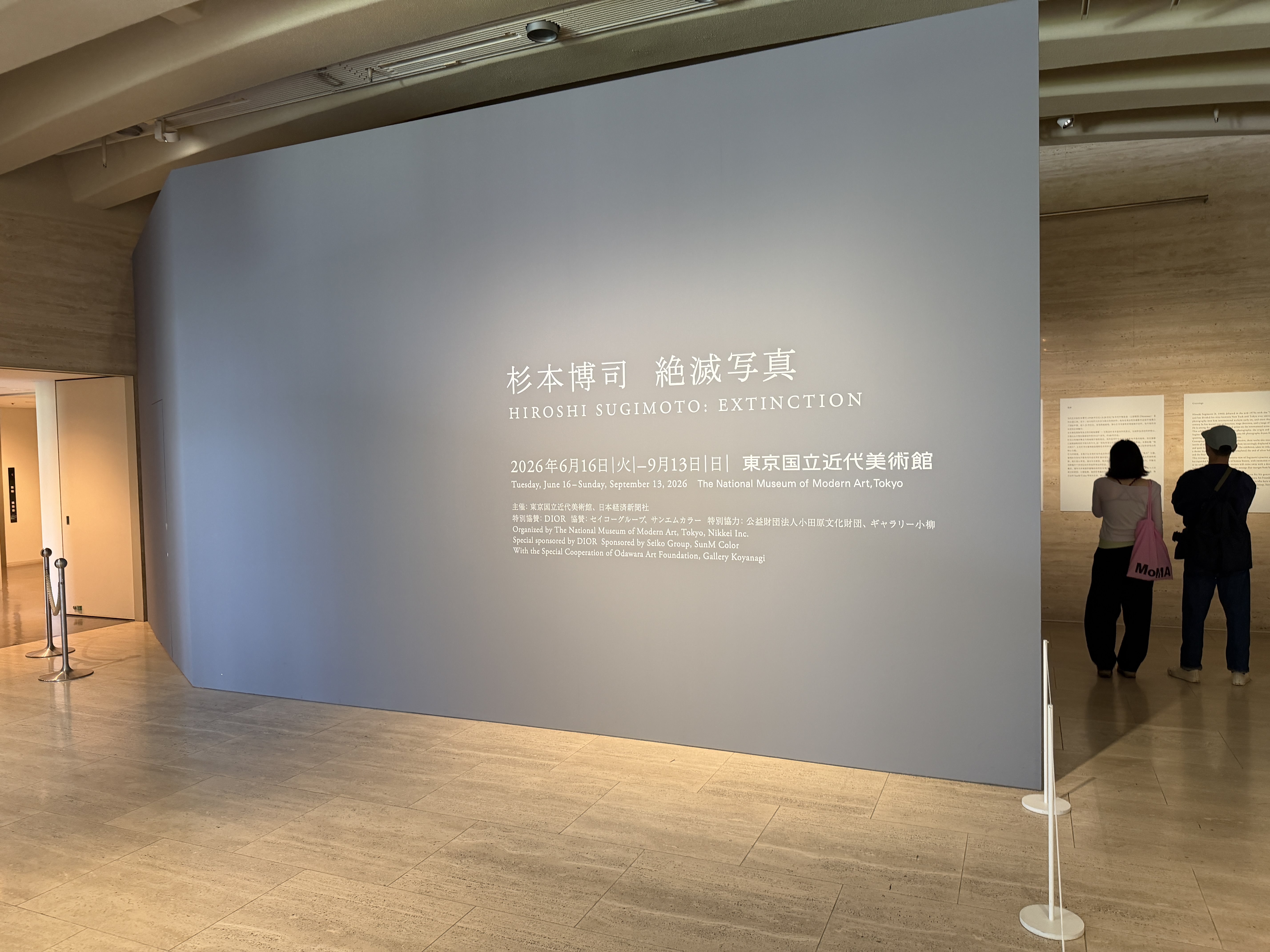 淡いブルーグレーの巨大な壁に展覧会タイトルが掲げられた会場入口