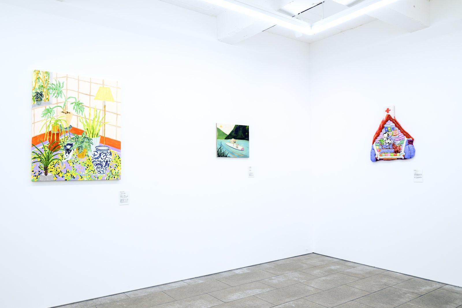 左にタムロアヤノの植物と犬を描いた油彩画、右に青山夢の家のかたちをした布のレリーフ作品が掛かるコーナー