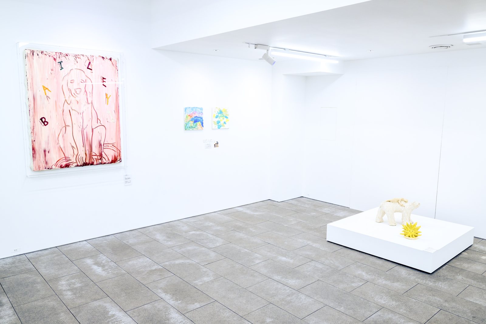 淡いピンクの大きな絵画が壁に掛かり、その手前の白い台に陶の犬が置かれた展示風景